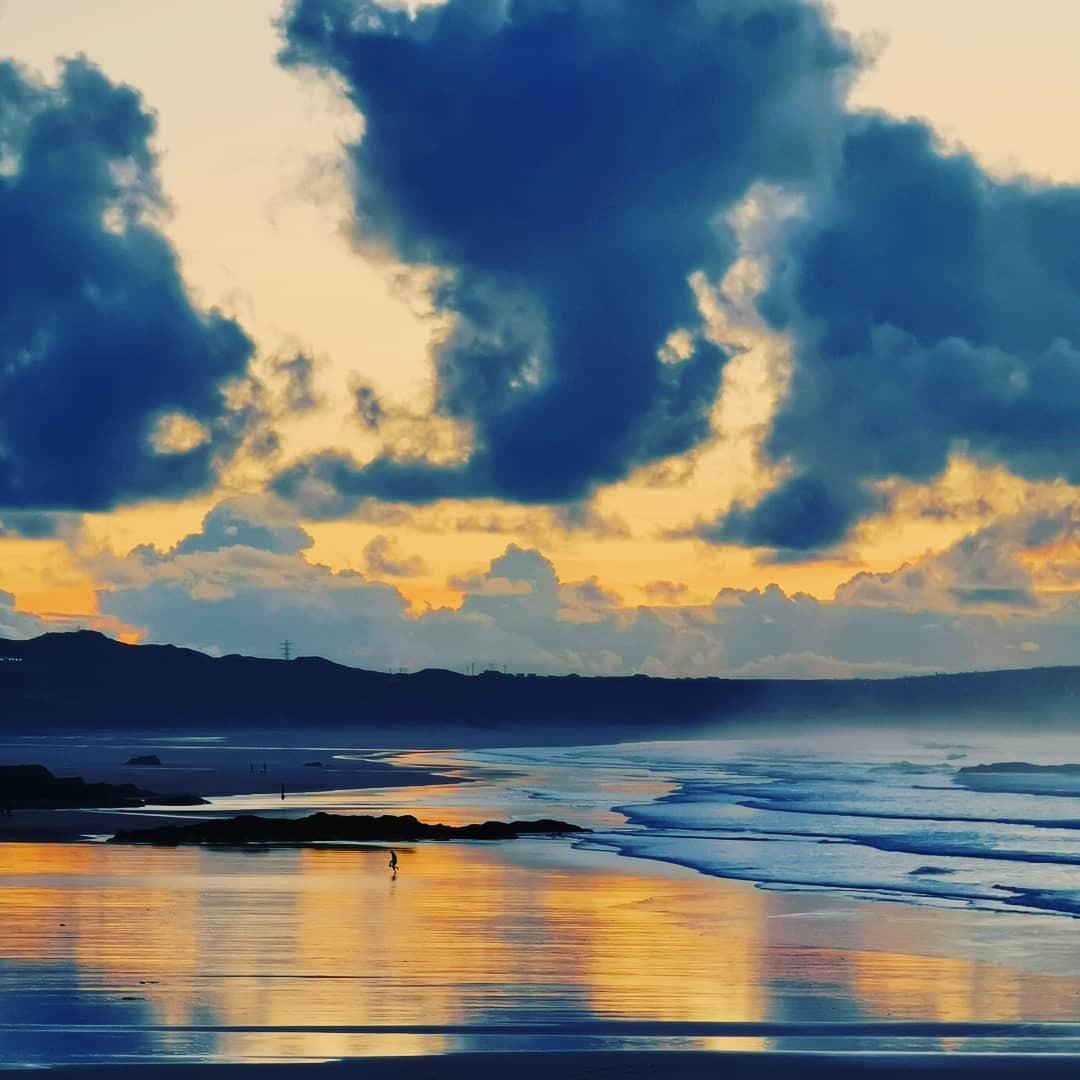Sunset over a wet beach, with colour-graded orange sky and teal cloud